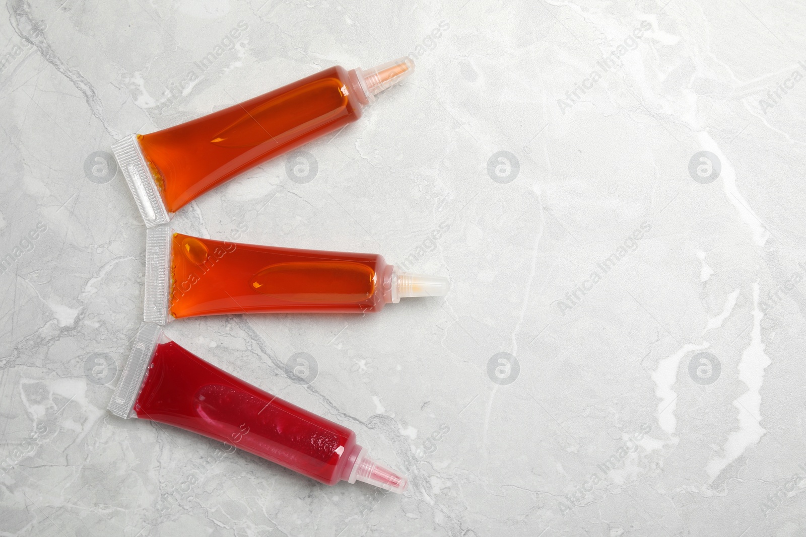 Photo of Tubes with food coloring on light grey marble table, flat lay. Space for text