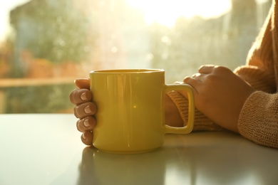 Woman with elegant cup at table at home, closeup