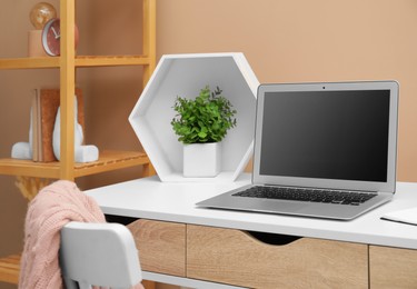 Photo of Cozy workplace with laptop and houseplant on desk at home