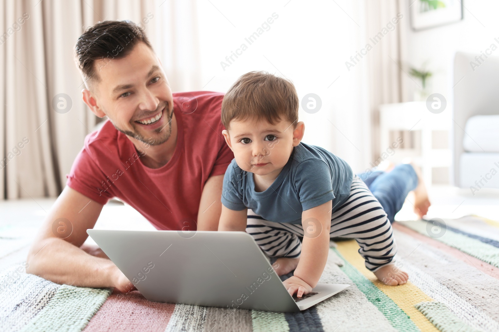 Photo of Dad and his son with laptop on carpet at home