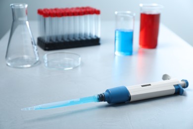 Photo of Laboratory analysis. Micropipette, beakers with liquids and other glassware on grey table