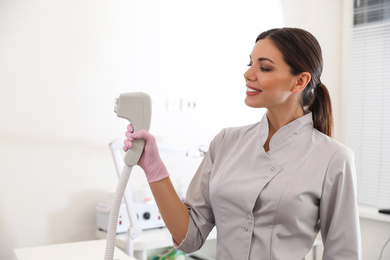 Young woman holding professional laser epilator in beauty salon