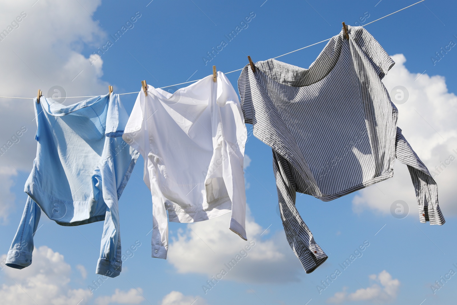 Photo of Clean clothes hanging on washing line against sky. Drying laundry