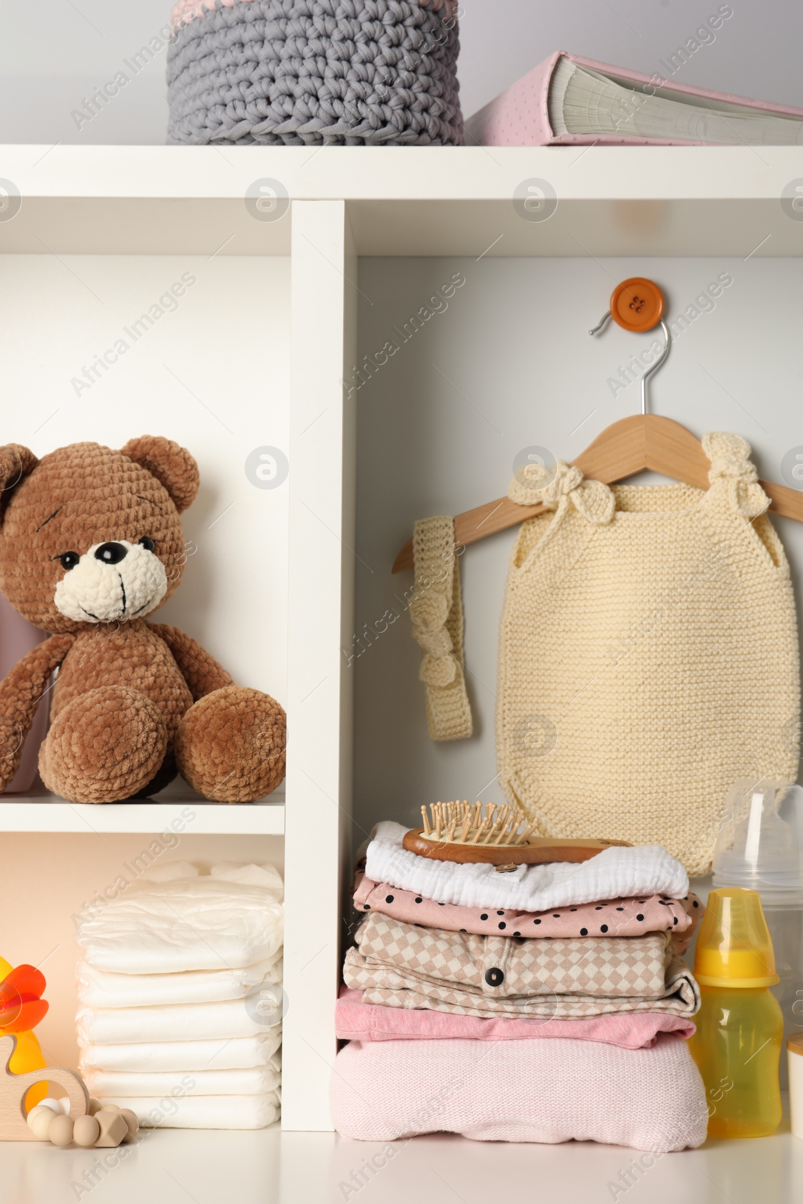 Photo of Baby clothes, toys and accessories on white rack