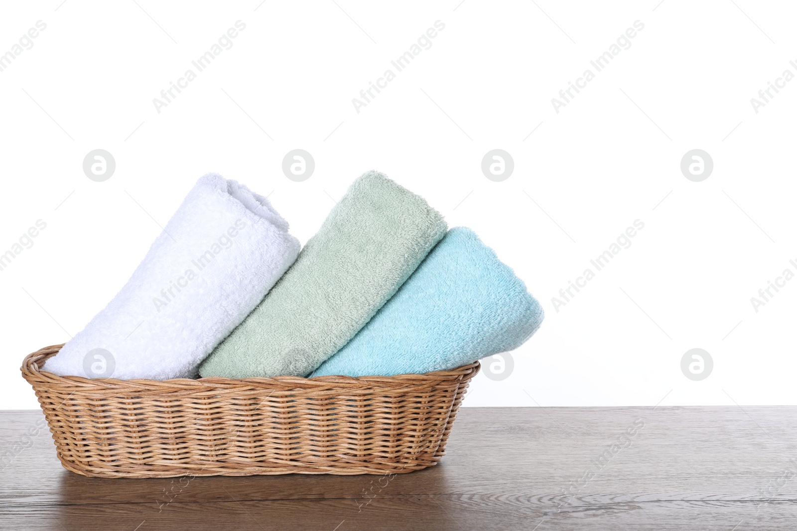 Photo of Fresh towels on wooden table against white background