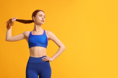 Photo of Young woman wearing sportswear on yellow background, space for text