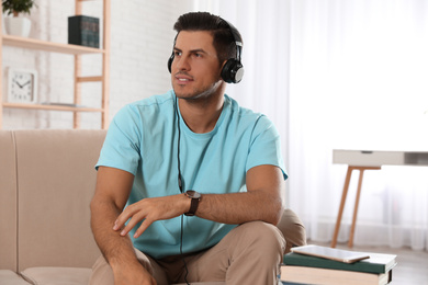 Photo of Man listening to audiobook on sofa at home