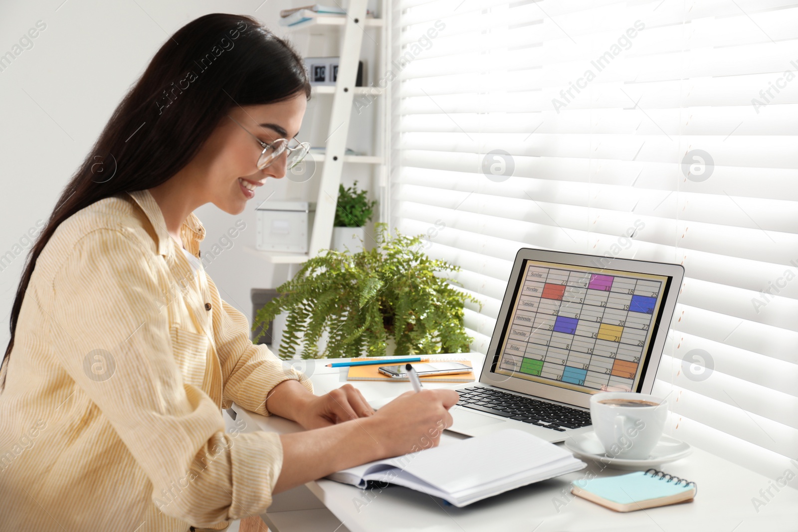 Photo of Young woman planning her schedule with calendar app on laptop in office