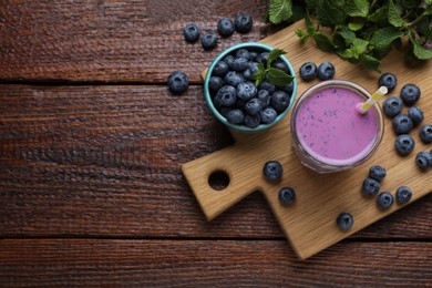 Photo of Glass of blueberry smoothie with mint and fresh berries on wooden table, flat lay. Space for text