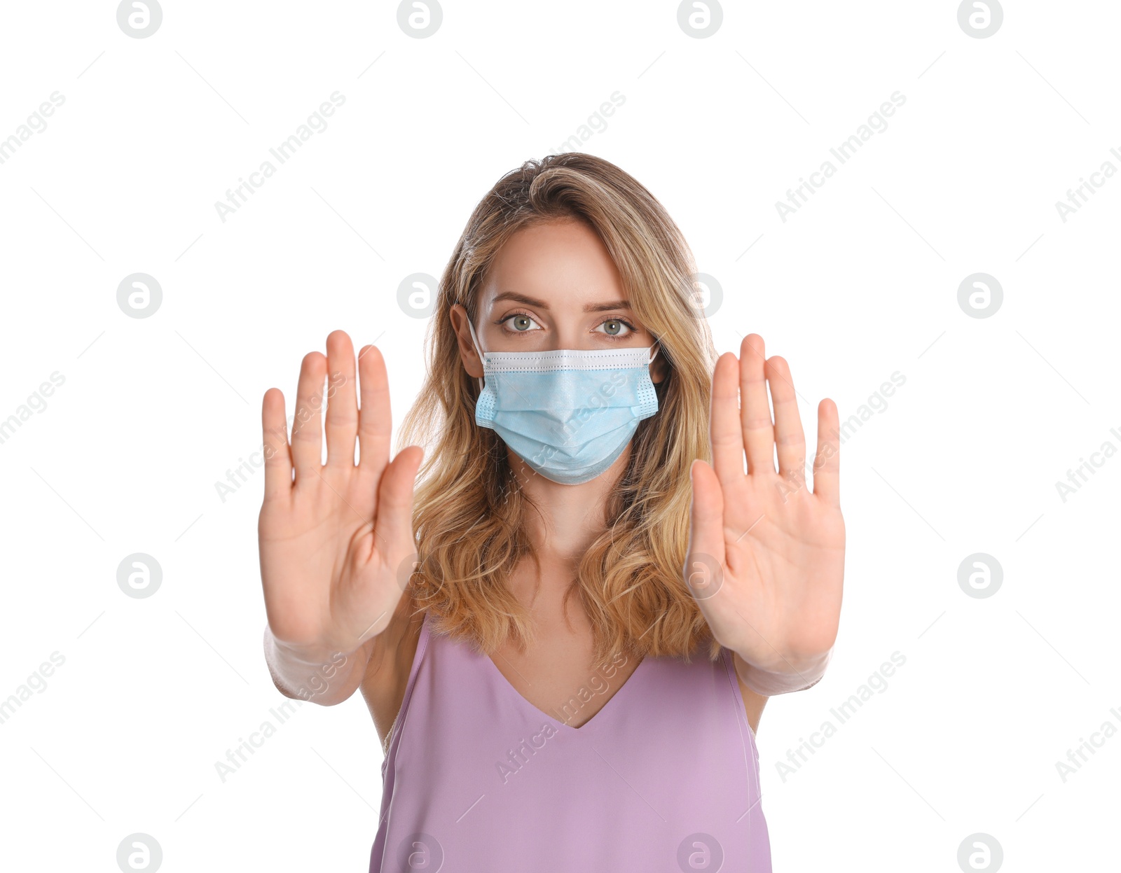 Photo of Woman in protective face mask showing stop gesture on white background. Prevent spreading of coronavirus