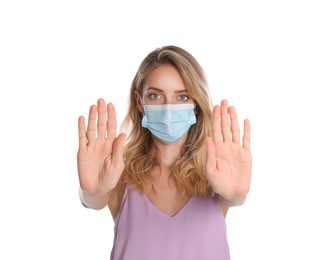 Photo of Woman in protective face mask showing stop gesture on white background. Prevent spreading of coronavirus