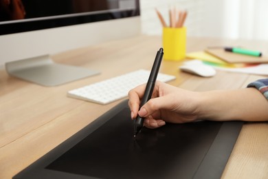 Professional designer working on graphic tablet at desk, closeup