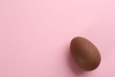 Sweet chocolate egg on pink background, top view. Space for text