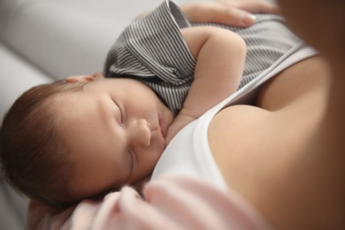 Photo of Young woman holding her newborn baby, closeup