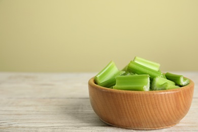 Photo of Cut celery in bowl on white wooden table. Space for text