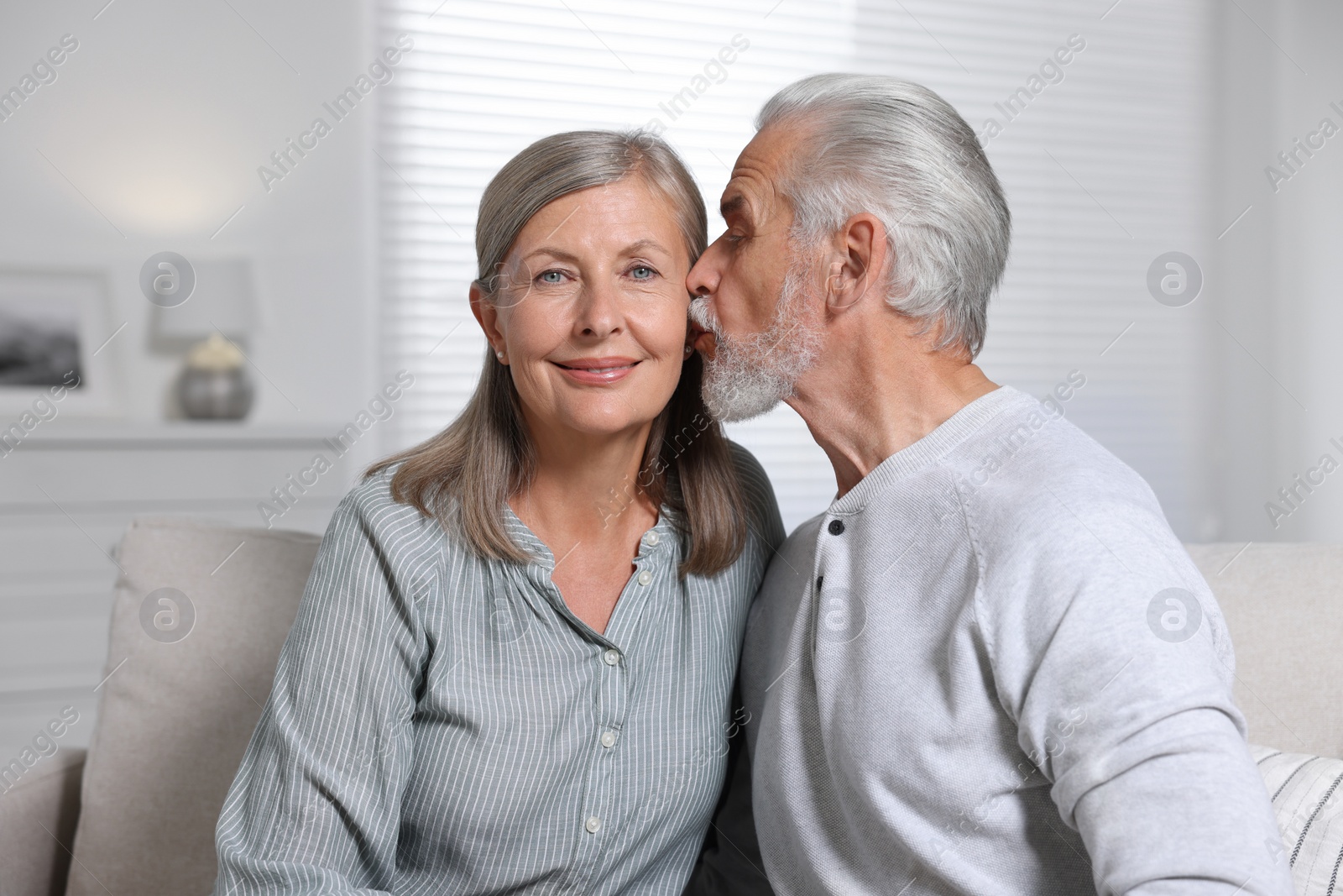 Photo of Senior man kissing his beloved woman at home