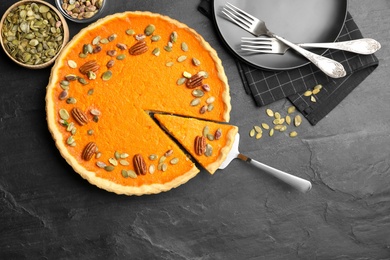 Photo of Delicious homemade pumpkin pie on black table, flat lay