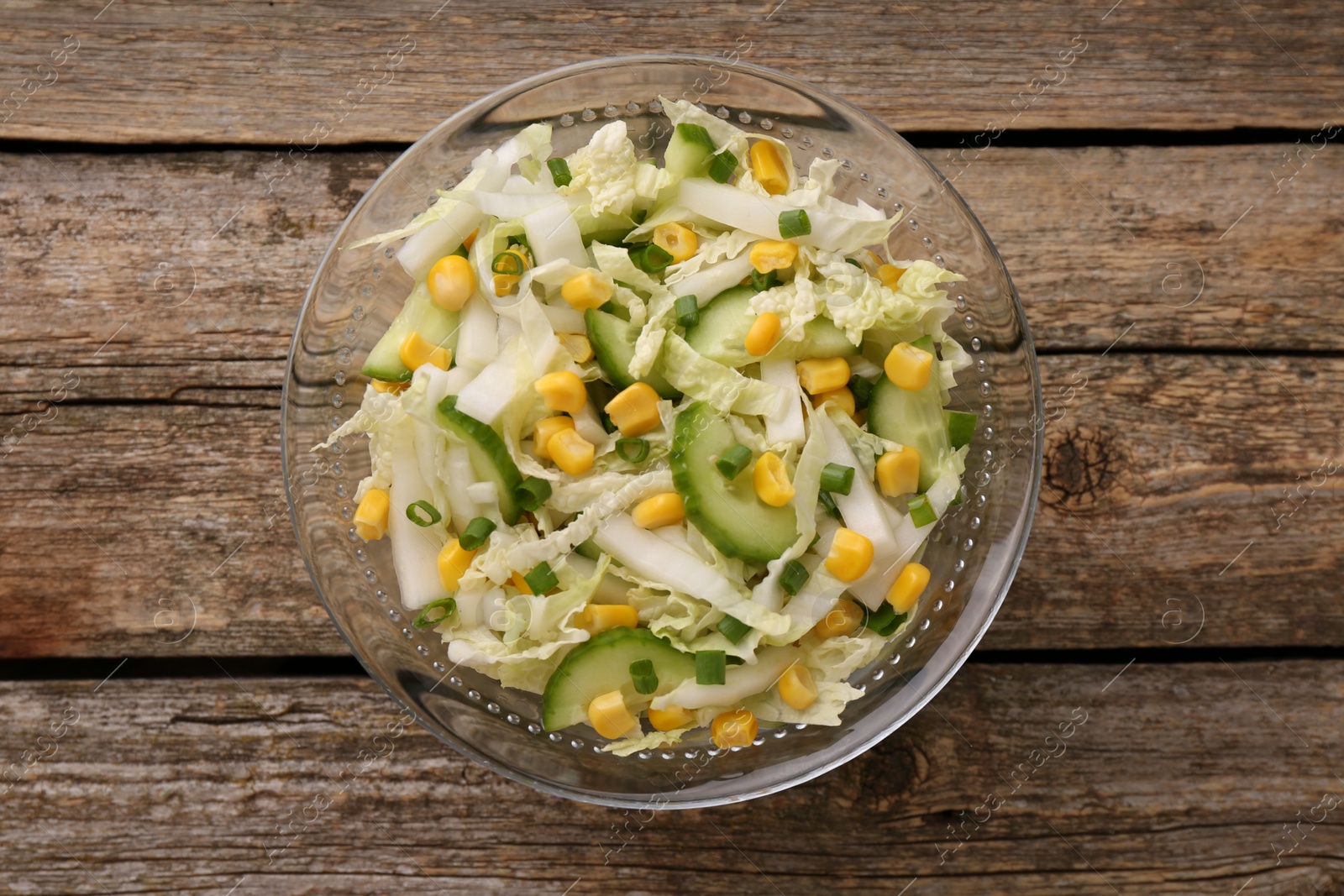 Photo of Tasty salad with Chinese cabbage, corn and cucumber in bowl on wooden table, top view