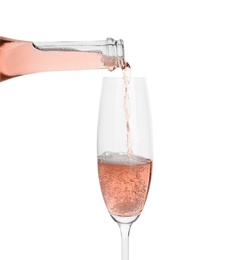 Photo of Pouring rose champagne from bottle into glass on white background