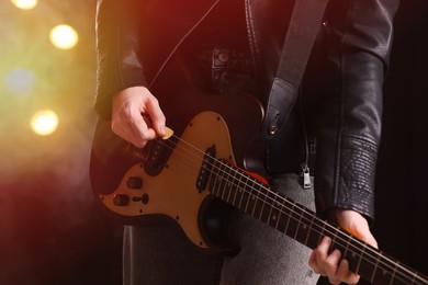 Photo of Man playing electric guitar on stage, closeup. Rock concert