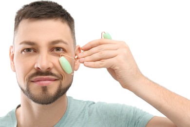 Man using nephrite facial roller on white background