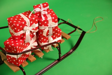 Sleigh with gift boxes on green background, closeup