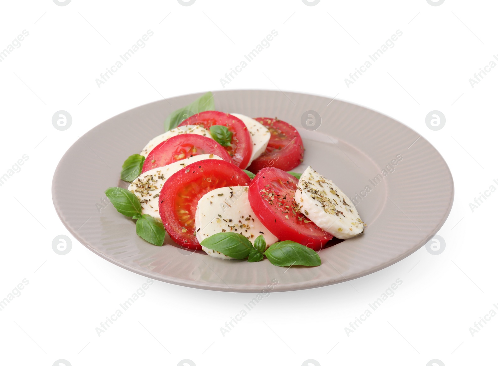 Photo of Plate of delicious Caprese salad with tomatoes, mozzarella, basil and spices isolated on white