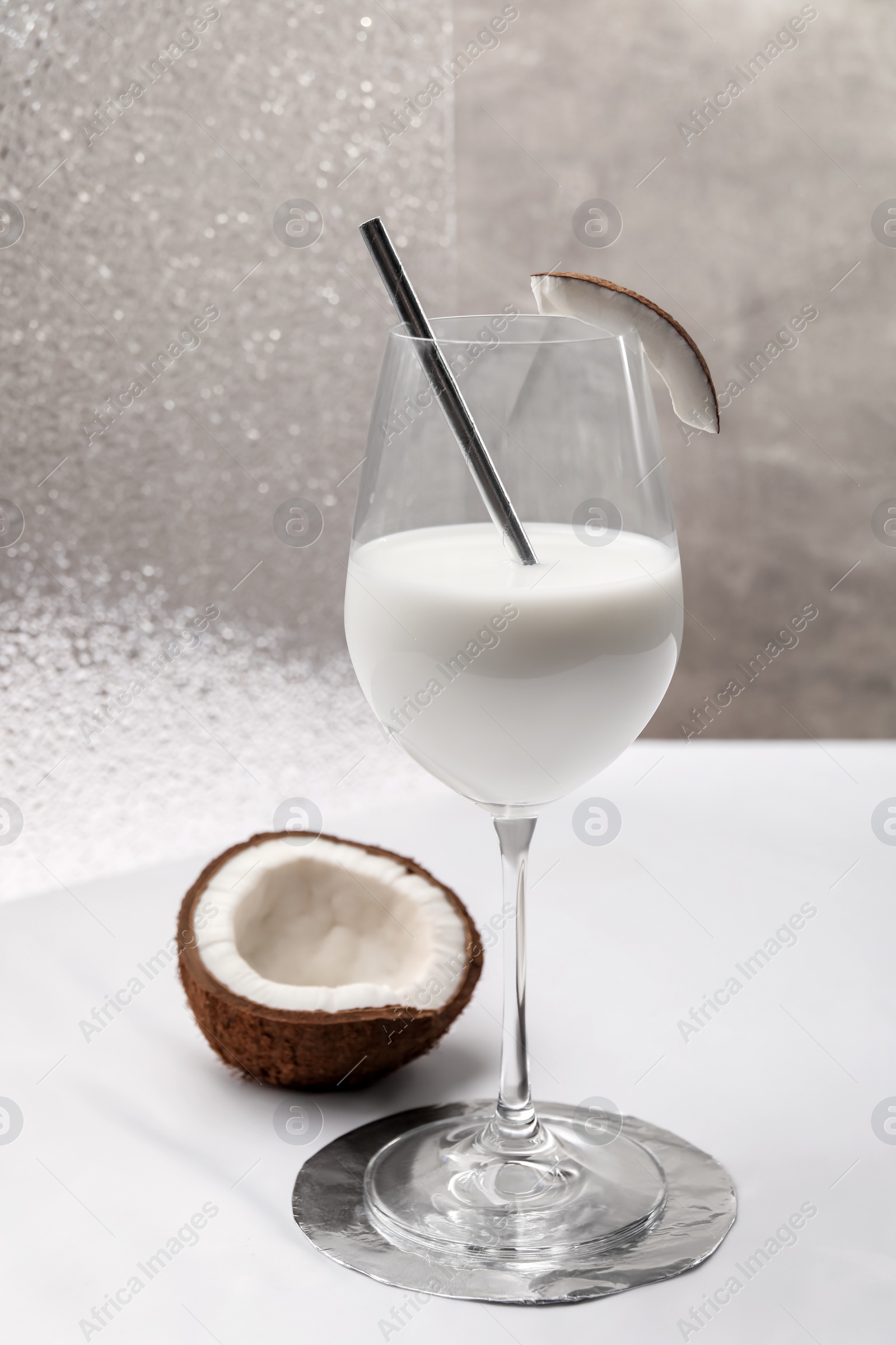 Photo of Glass of delicious coconut milk and coconut on white table