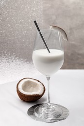 Glass of delicious coconut milk and coconut on white table