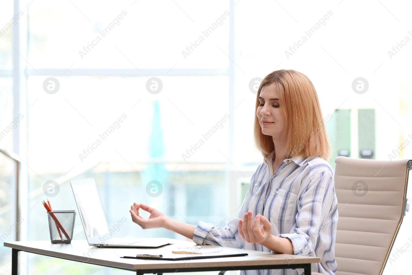 Photo of Beautiful woman meditating at table in office during break, space for text. Zen yoga