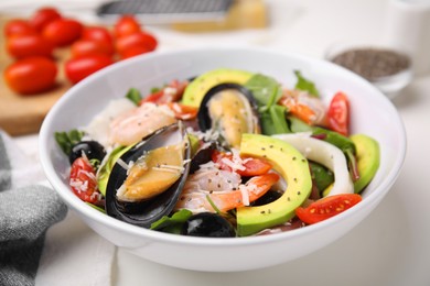 Photo of Bowl of delicious salad with seafood on white table, closeup