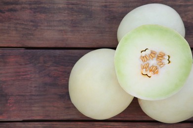 Photo of Whole and cut fresh ripe melons on wooden table, flat lay. Space for text