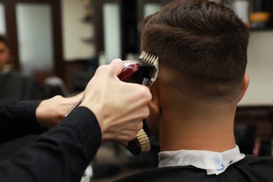 Photo of Professional hairdresser making stylish haircut in salon, back view