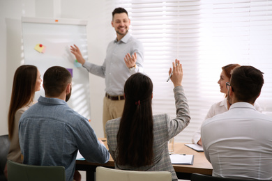 Young woman raising hand to ask question at business training in conference room