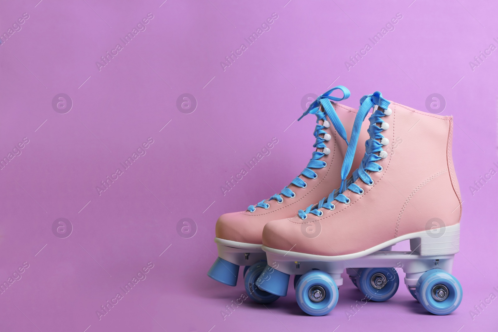 Photo of Pair of stylish quad roller skates on color background. Space for text