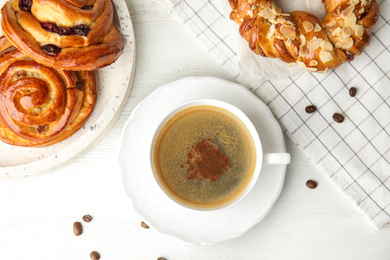 Fresh tasty pastries and coffee on white wooden table, flat lay