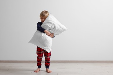 Photo of Little boy hugging pillow indoors, space for text