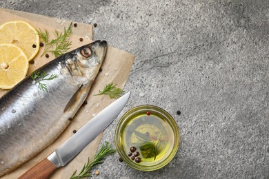 Photo of Delicious salted herring, olive oil, lemon and rosemary on grey table, flat lay. Space for text