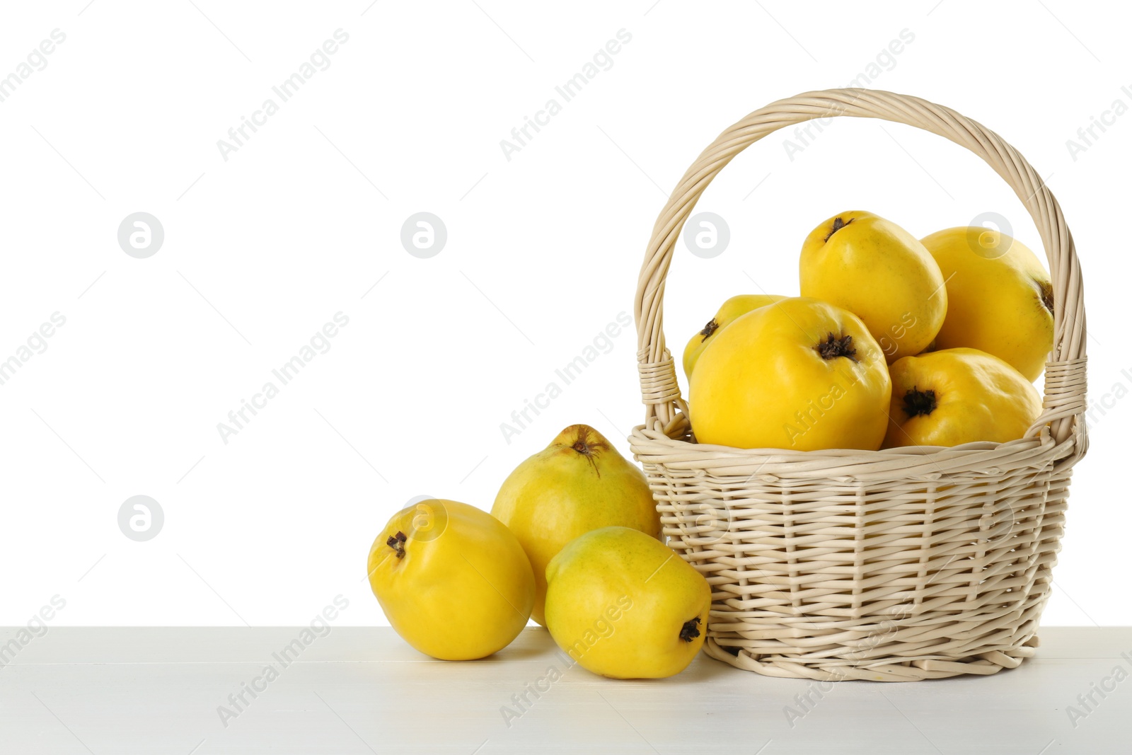 Photo of Basket with delicious fresh ripe quinces on light wooden table against white background, space for text