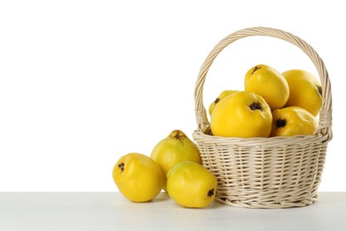 Photo of Basket with delicious fresh ripe quinces on light wooden table against white background, space for text
