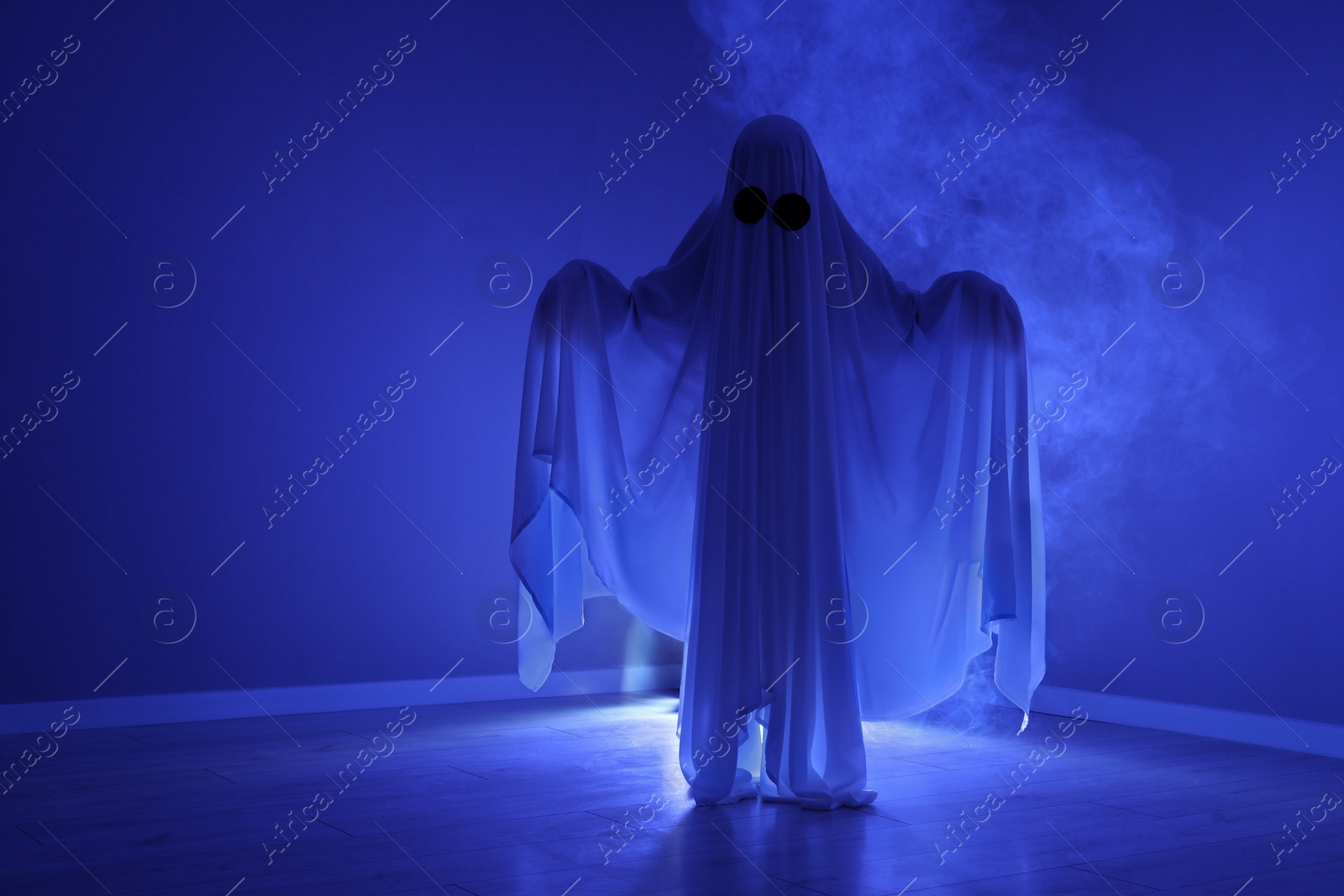 Photo of Creepy ghost. Woman covered with sheet in blue light, space for text