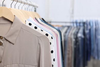 Dry-cleaning service. Many different clothes hanging on rack indoors, closeup