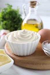 Photo of Fresh mayonnaise sauce in bowl and ingredients on table