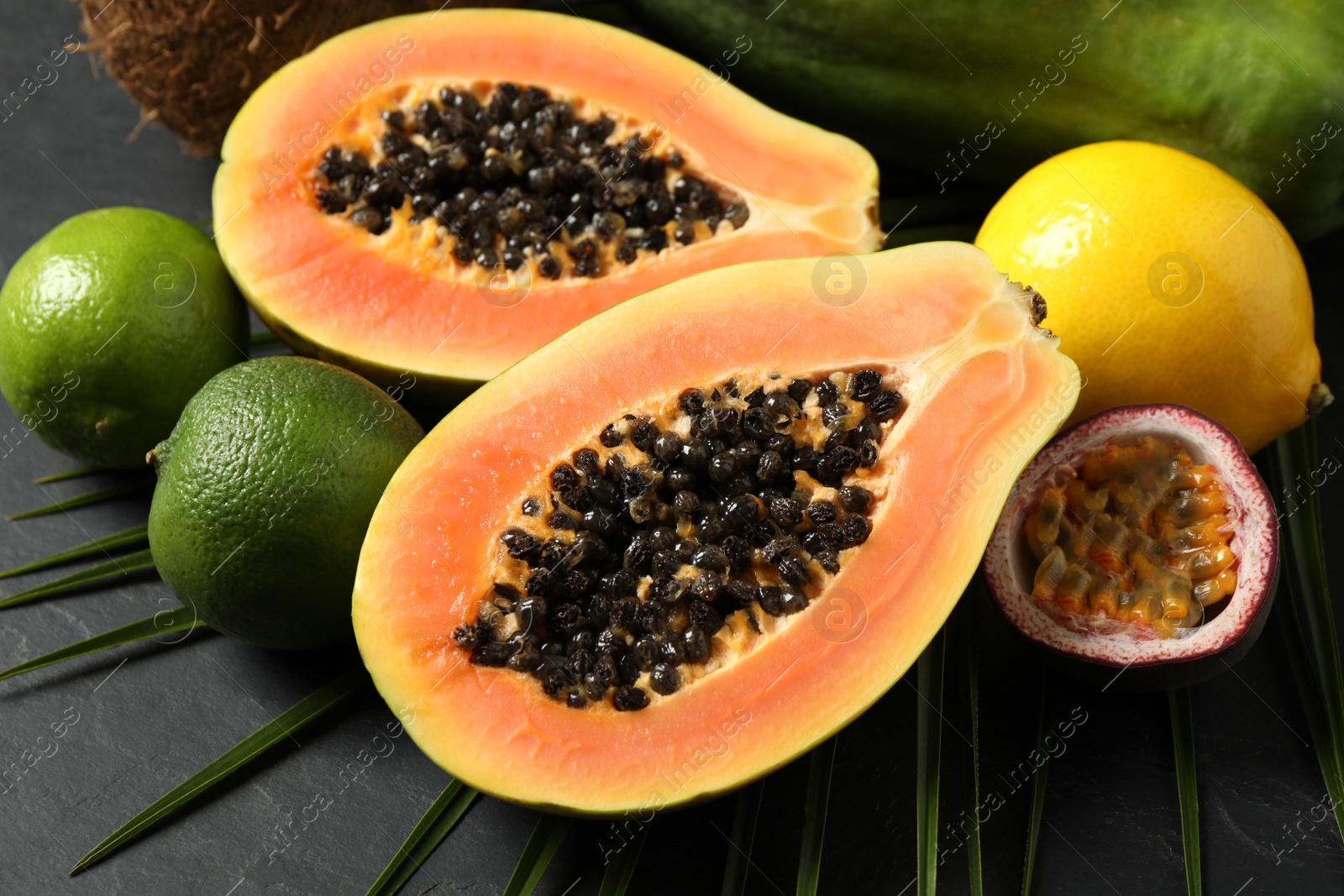 Photo of Fresh ripe papaya and other fruits on black table