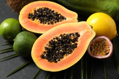 Fresh ripe papaya and other fruits on black table