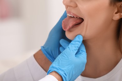 Doctor examining woman`s oral cavity on blurred background, closeup