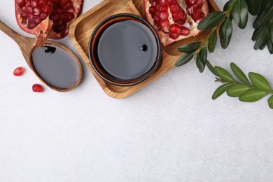 Photo of Tasty pomegranate sauce, fruits and branches on light table, flat lay. Space for text