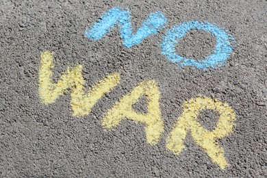Photo of Words No War written with blue and yellow chalks on asphalt outdoors