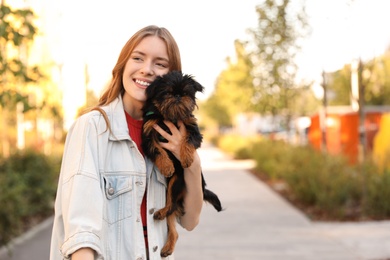 Photo of Young woman with adorable Brussels Griffon dog in park. Space for text
