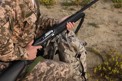 Photo of Man wearing camouflage with hunting rifle outdoors, closeup